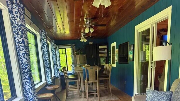Quarto com banco embutido, sofá, mesa de jantar e ventilador de teto.