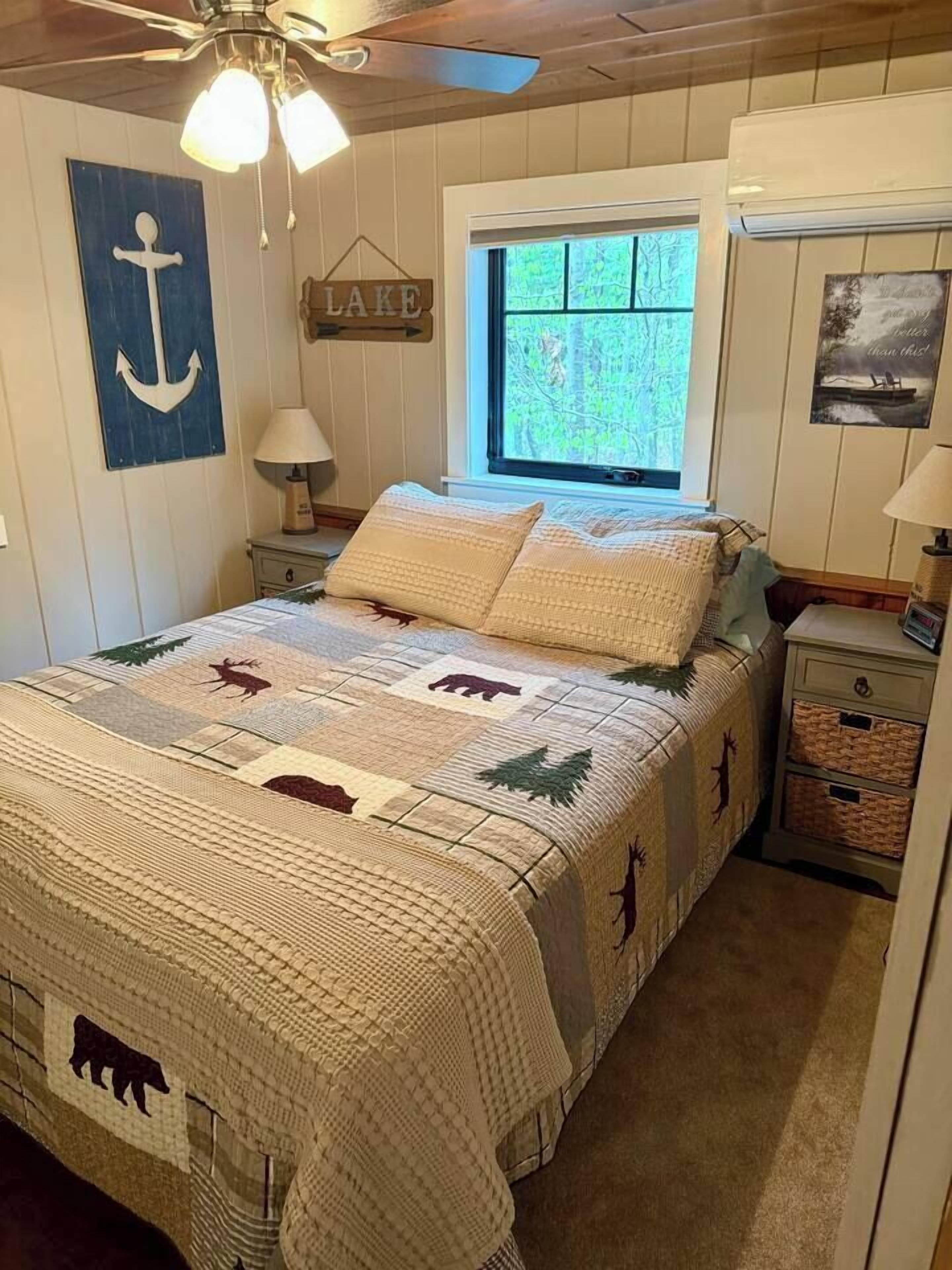 A bedroom with a bed, a window, a wall-mounted sign, and a ceiling fan.