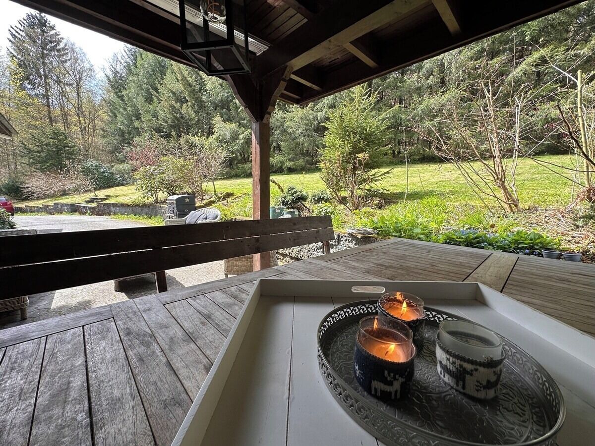 An outdoor seating area with a wooden bench and a table with candles.