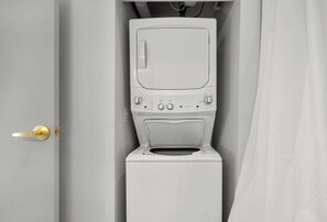 Eine weiße Waschmaschine in einem Badezimmer, eine Tür ist links zu sehen.