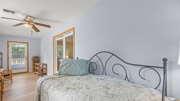 A bedroom with a bed, a ceiling fan, a window, and a door. - SH30: Southern Shores 30 (Southern Shores)