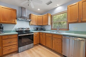 A kitchen with wooden cabinets, a stainless steel oven, a microwave, and a dishwasher. - SH30: Southern Shores 30 (Southern Shores)