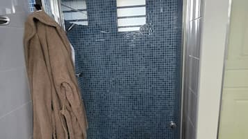 Ein Badezimmer mit Dusche, Handtuchhalter und einer Sitzbank.