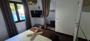 Een hotelkamer met een bed, een televisie, een tafeltje en een raam met gordijnen.