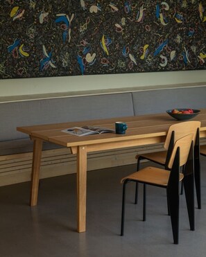 A dining area with a wooden table and black chairs, a bowl of fruit, and a magazine on the table. - Skyfall - Modern Chalet | Sleeps 10 | Unique Design | View (Les Houches)