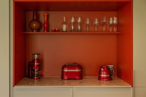 A kitchen with a red cabinet containing a coffee maker, a red kettle, and a red appliance. - Skyfall - Modern Chalet | Sleeps 10 | Unique Design | View (Les Houches)