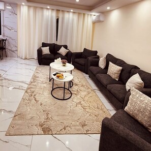 Ein Wohnzimmer mit Marmorboden, zwei Sofas, einem Couchtisch und einem gemusterten Teppich.