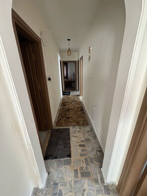 A hallway with a patterned rug, stone flooring, and a door on the left. - 3-bedroom apartment in enjoyable Amman with AC for relaxing stay (Amman)