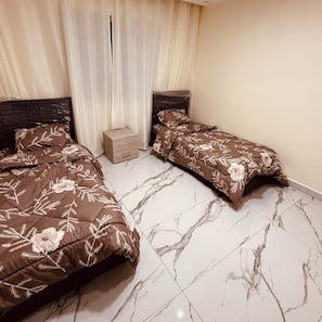 A room with two beds, a small wooden nightstand, and a window with curtains. - 3-bedroom apartment in enjoyable Amman with AC for relaxing stay (Amman)
