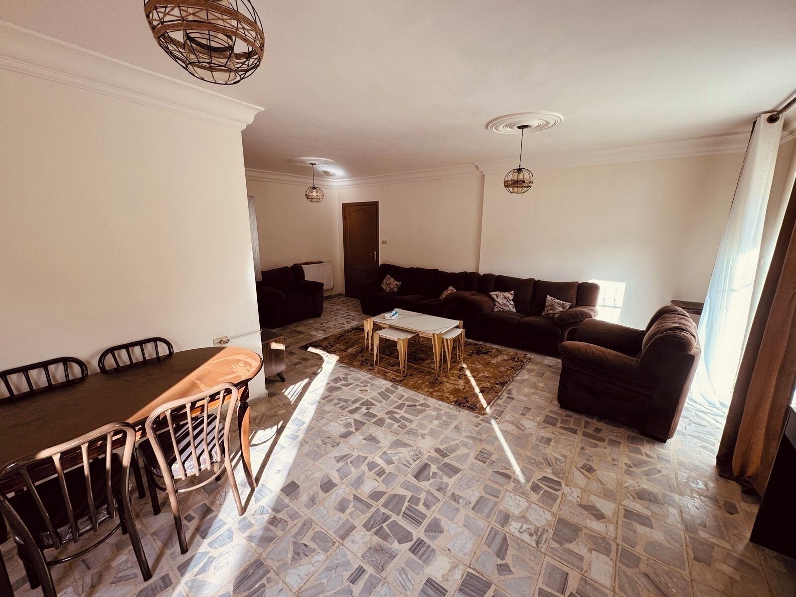 A living room with a sofa, coffee table, and dining area with chairs and a table.