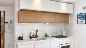 Eine moderne Küche mit weißen Schränken, einer Marmor-Spritzschutzwand und einer schwarzen Induktionskochplatte.
