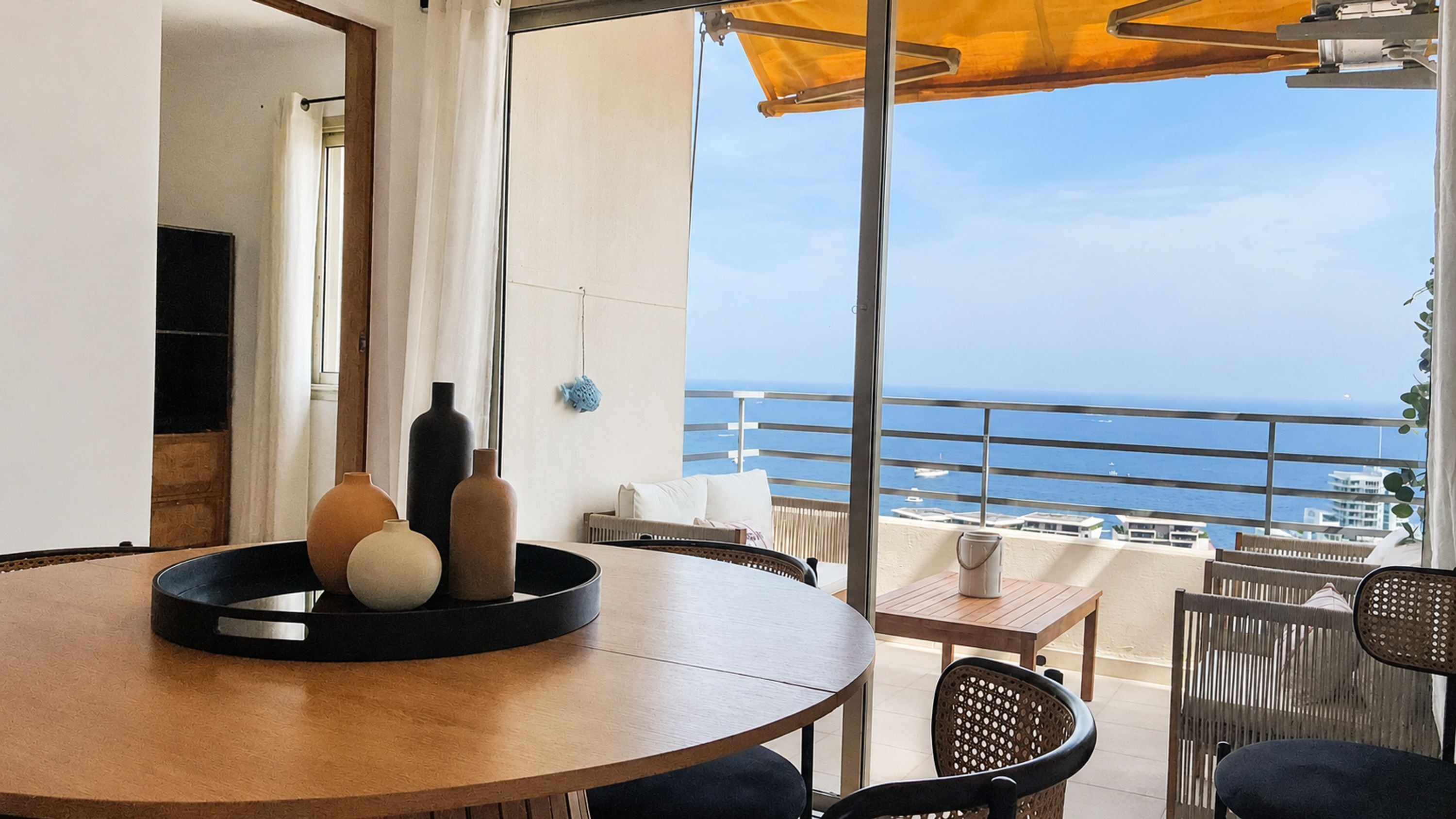 A round table with a black tray, a sofa, and a view of the sea.
