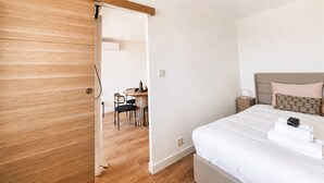 Ein Schlafzimmer mit Bett, Nachttisch, Holztür und einem Essbereich mit Tisch und Stühlen.
