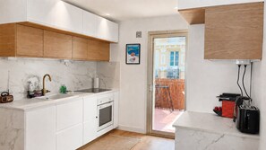 Una cocina moderna con armarios blancos, encimera de mármol y horno empotrado.