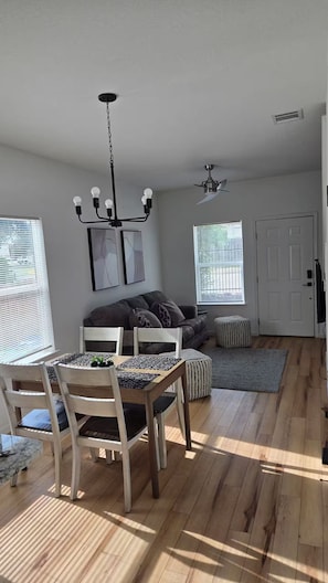A spacious living area with a dining table, chairs, a sofa, and a ceiling fan. - Rezidence Townhome at Dignowity (San Antonio)