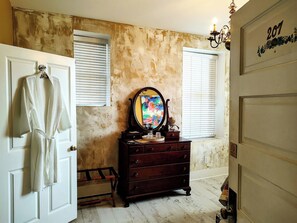 Une pièce avec une commode en bois, un miroir et un peignoir accroché à une porte.