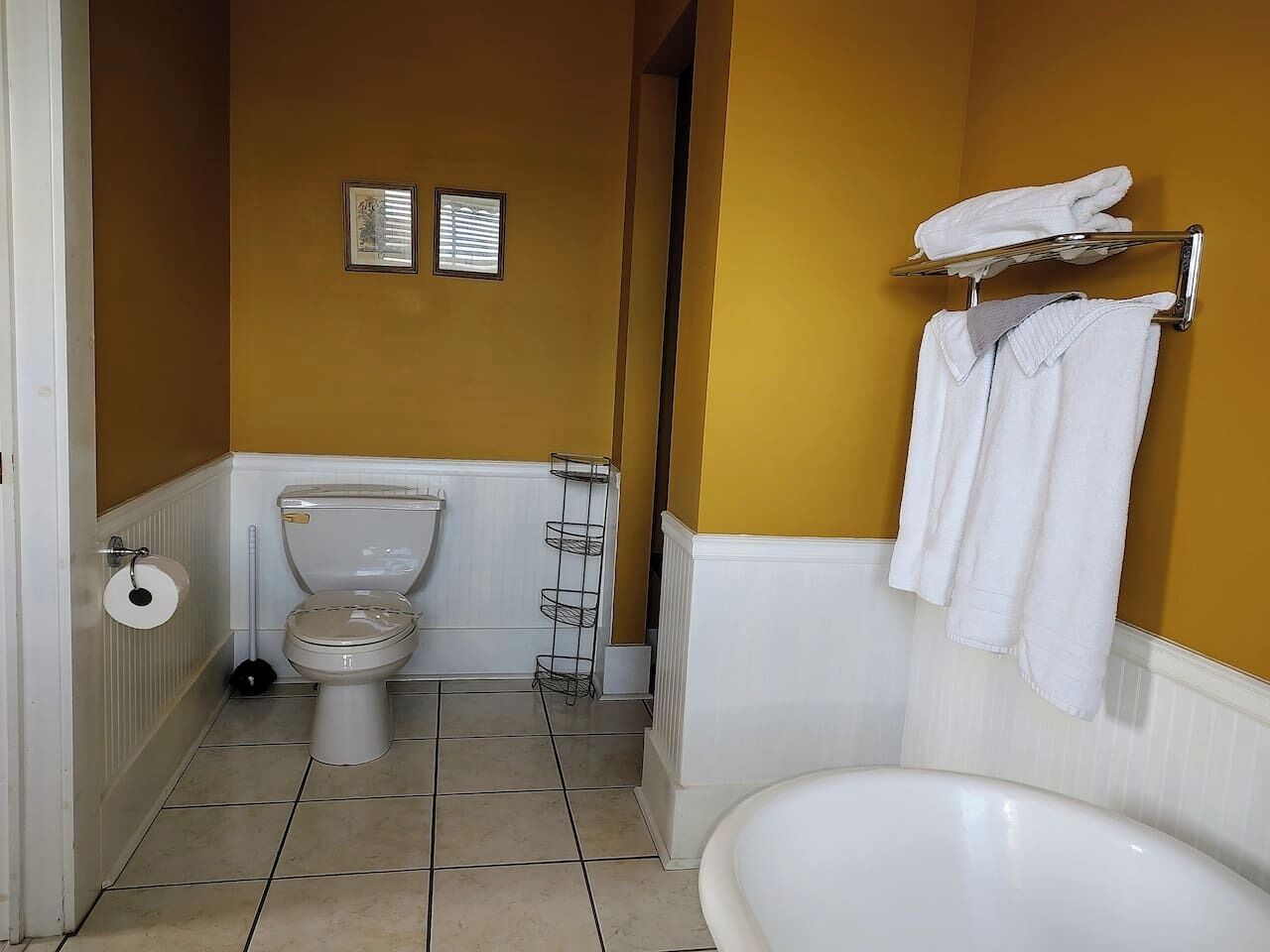 A bathroom with a toilet, a sink, and a bathtub. There are towels hanging on a rack.