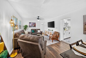 A modern living room with a sofa, armchairs, a coffee table, and a dining table set for four. - Fabulous 5BR 2BA "Legends of Notre Dame" Home 1.5m from Campus! Walk in 30 mins! (South Bend)