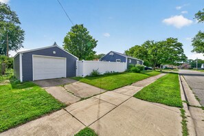 A residential street with houses, a garage, and a sidewalk. - Fabulous 5BR 2BA "Legends of Notre Dame" Home 1.5m from Campus! Walk in 30 mins! (South Bend)