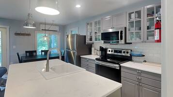 A modern kitchen with stainless steel appliances, a white countertop, and a dining area with a table and chairs.