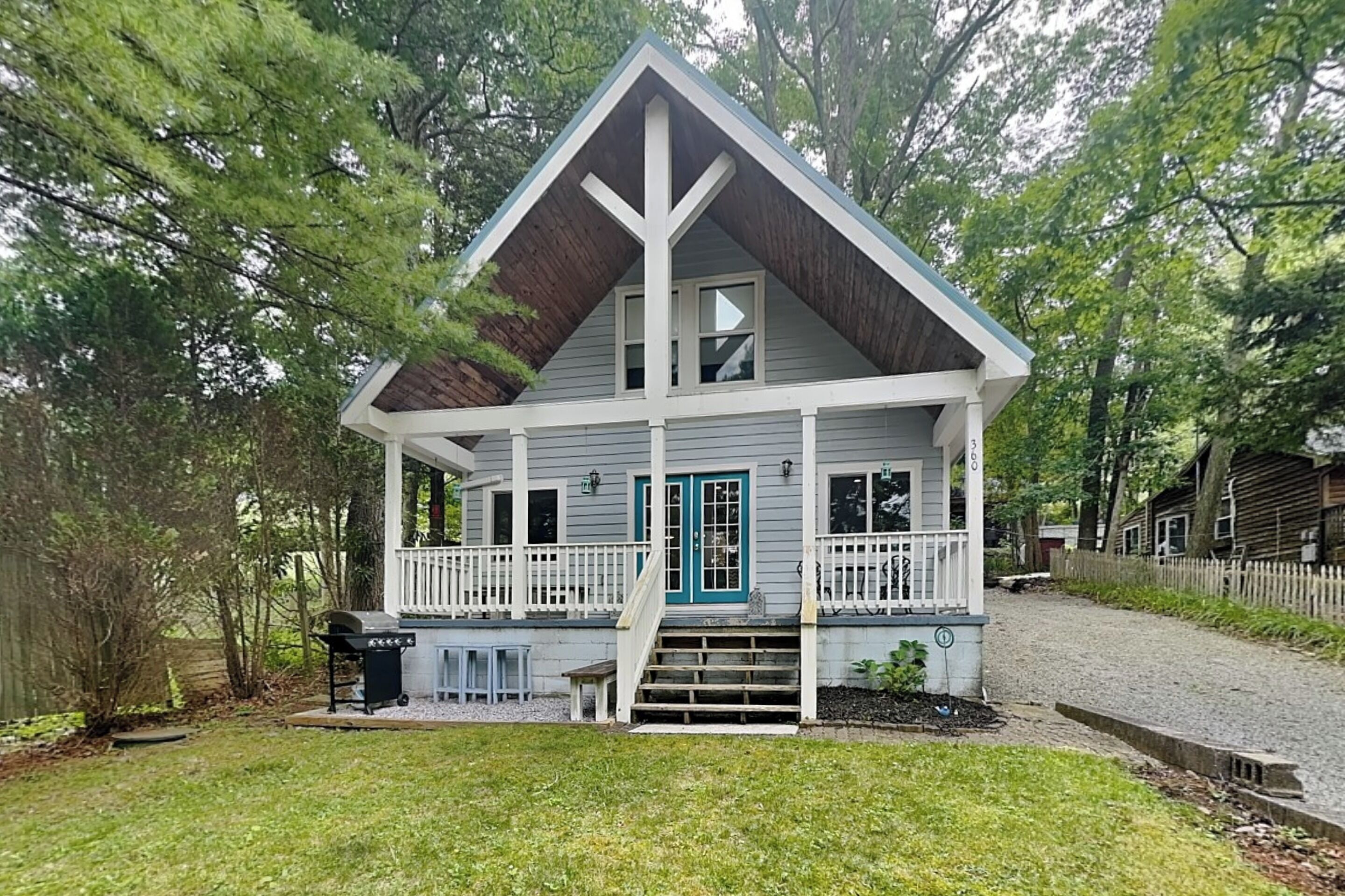 A two-story house with a porch, a blue door, and a small front yard.