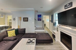 A modern living room with a sectional sofa, a flat-screen TV, and a fireplace. - Winter Green Lodge (McHenry)