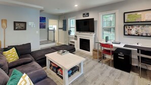 Ein modernes Wohnzimmer mit Kamin, Fernseher und Schreibtisch.