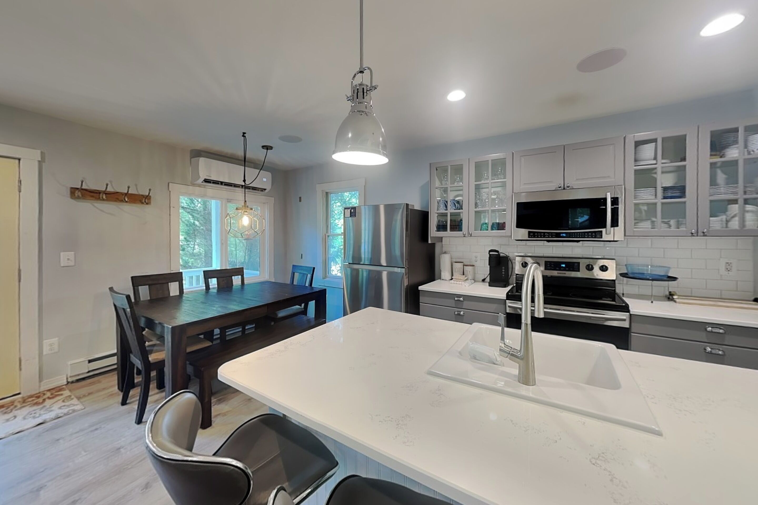 A modern kitchen with a central island, stainless steel appliances, and a dining area with a wooden table and chairs.