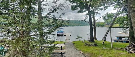Une vue sur le lac avec un quai, un bateau et une table de pique-nique.
