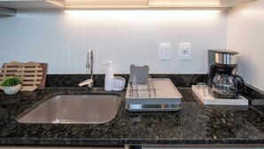 A modern kitchen with a stainless steel sink, a coffee maker, and a built-in dishwasher. - Corporate Stays First del Sol - 202 (Asunción)