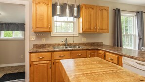 A kitchen with wooden cabinets, a granite countertop, a double sink, and a built-in dishwasher.