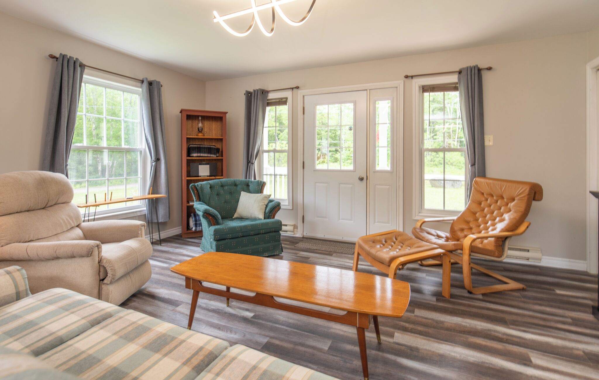 A spacious living room with a sofa, armchair, and a wooden coffee table.
