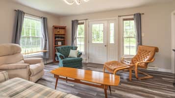 A spacious living room with a sofa, armchair, and a wooden coffee table.