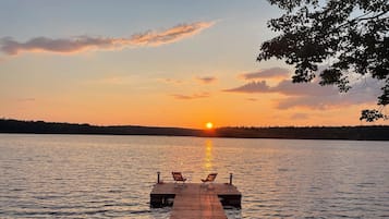 A wooden pier extending into calm water with a sunset in the background.