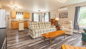 A compact living space with a kitchenette, a sofa, a chair, and a dining table.