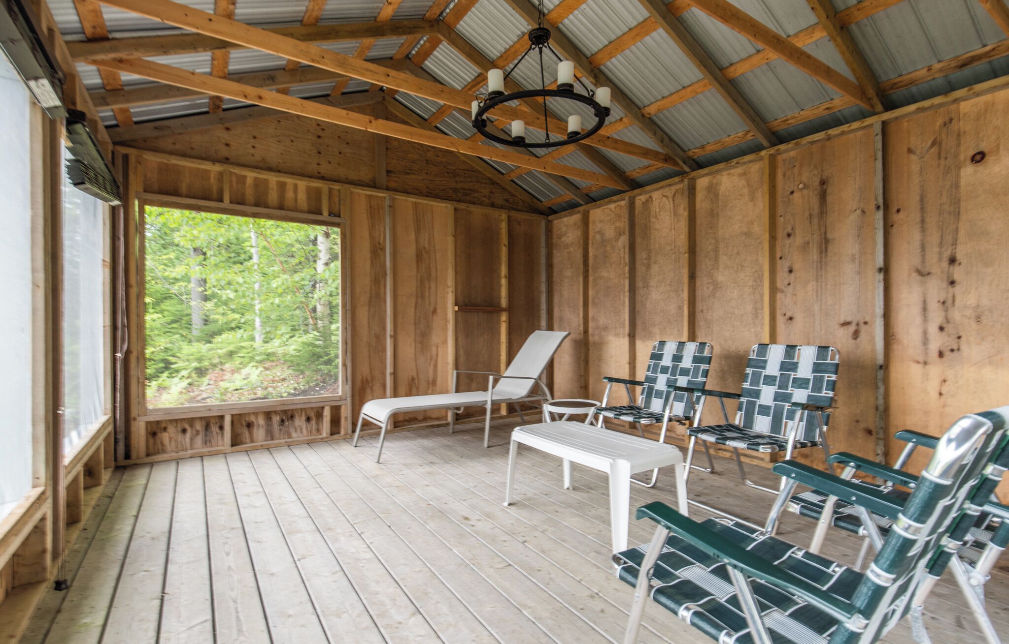 A wooden cabin with a wooden floor, a bench, and several chairs.