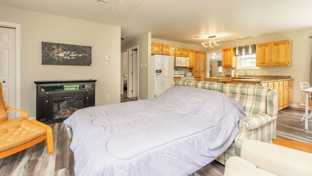 A cozy room with a bed, a fireplace, a sofa, and a kitchenette.
