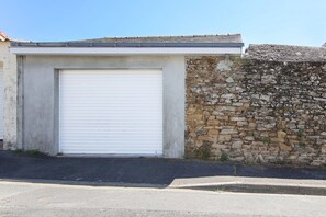 A building with a closed white garage door and a stone wall. - La Maisonnette de Cholet - Studio avec jardin (Cholet)