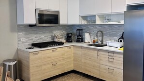 A modern kitchen with white cabinets, a stainless steel refrigerator, a built-in microwave, and a gas stove. - 2BR Luquillo Home Near Beach & El Yunque, A/C + Parking (Luquillo)