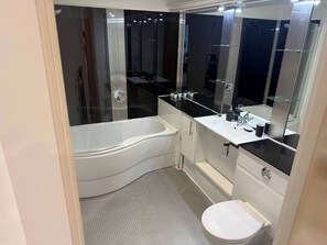 Ein modernes Badezimmer mit einer Eckbadewanne, einem weißen Waschbecken und einer Toilette.