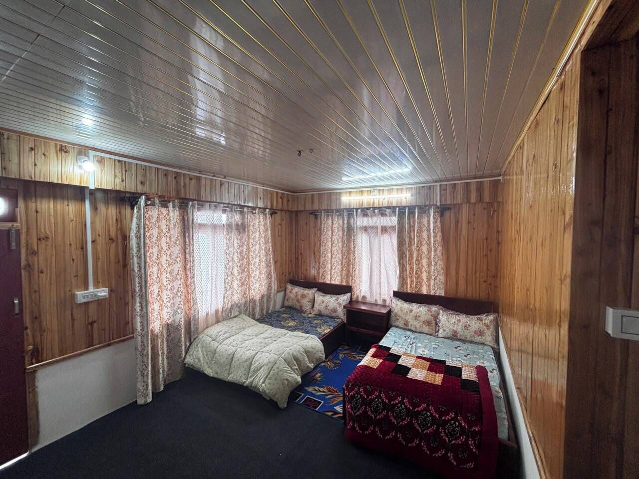 Et værelse med to senge, trævægge og et bjælkeklædt loft.