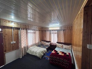 Una habitación con dos camas, paredes de madera y techo con vigas a la vista.