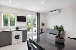A modern kitchen with a washing machine, a dining table, and a potted plant. - Chez Frédéric et Josiane - Bel appt avec terrasse (Montpellier)