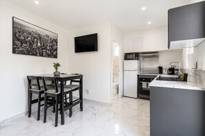 A modern kitchen with a dining area, a flat-screen TV, and a marble floor. - Chez Frédéric et Josiane - Bel appt avec terrasse (Montpellier)