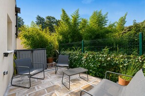 An outdoor patio with a table and chairs, surrounded by a green fence and lush foliage. - Chez Frédéric et Josiane - Bel appt avec terrasse (Montpellier)