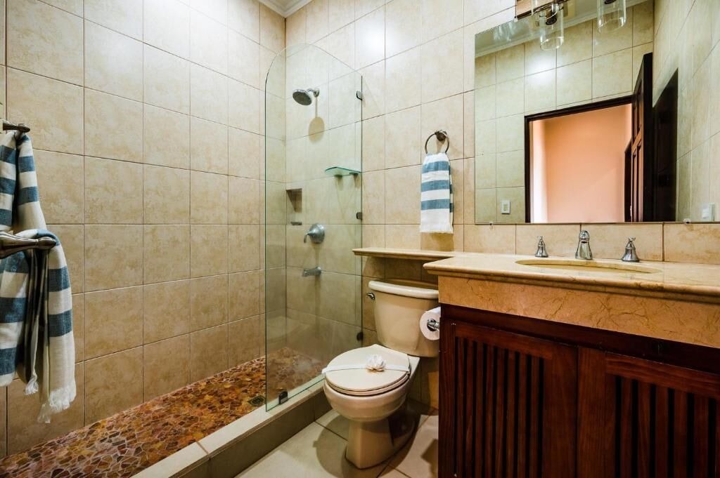 Ein Badezimmer mit einer Duschkabine, einer Toilette und einem Waschtisch mit Spiegel.