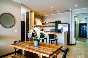 A modern kitchen with a central island, built-in appliances, and a dining area with a wooden table and chairs. - Stylish Oceanview Condo with Quick Beach Access, Modern Design & Spacious Balcony (Santa Cruz)