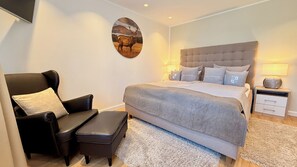A bedroom with a large bed, a chair, a nightstand, and a wall-mounted picture. - Haus-Holiday.de - Walkenried (Walkenried)