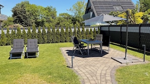 Un patio con mesa y sillas, una sombrilla y un sendero de ladrillo.