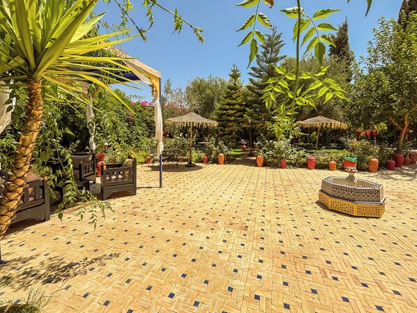 Un patio con suelo estampado, mobiliario exterior y plantas en macetas.